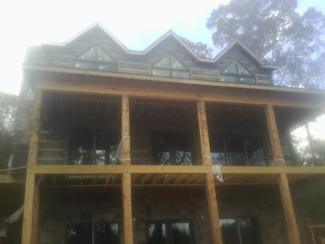 Dormers and porch framing on a large log home under construction — Roof Coating work by our crew in Barnesville