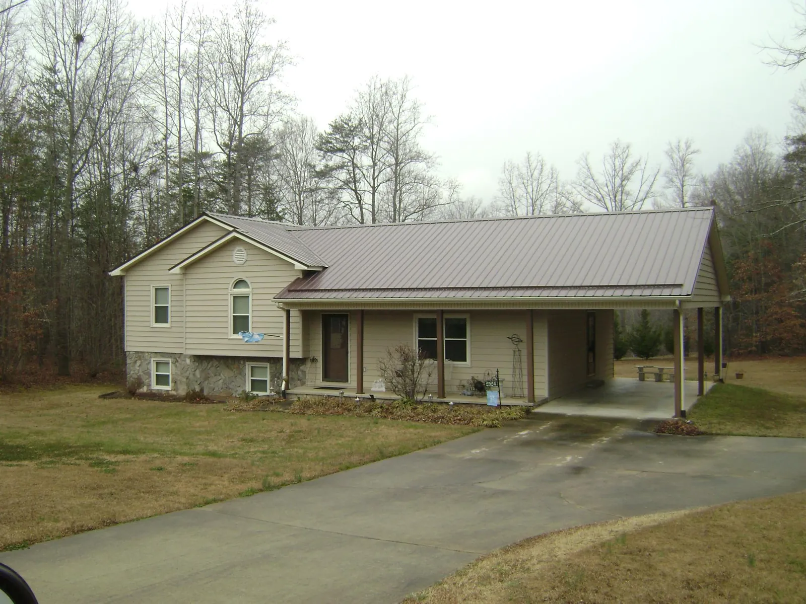 Brown metal roof on a tan split level home with an attached carport in Barnesville